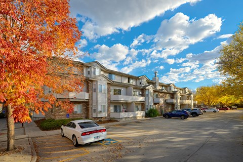 A white car is parked in a parking lot in front of a building.